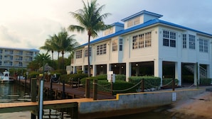 A waterfront hotel with a covered outdoor area, palm trees, and a dock.