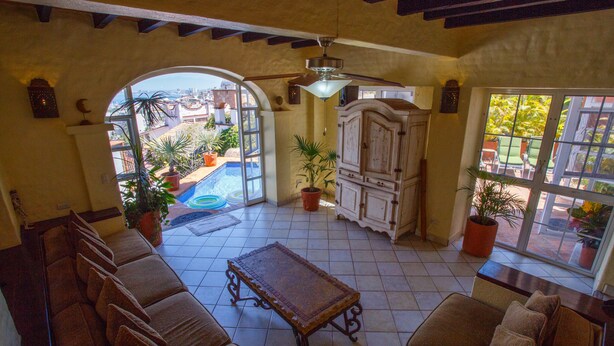 Uma sala de estar ampla com vista para uma piscina, um ventilador de teto e um armário grande.