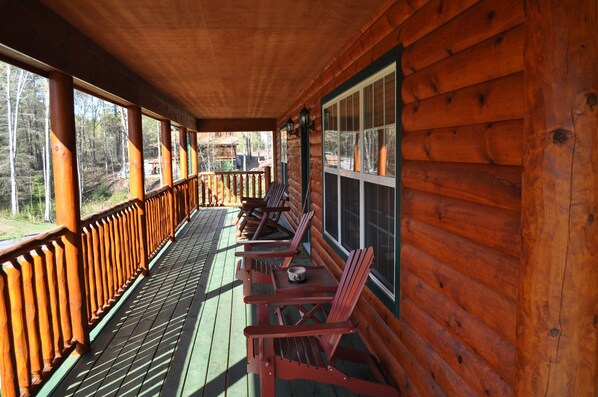 Una cabana de fusta amb un porxo cobert, baranes de fusta i diverses cadires Adirondack.