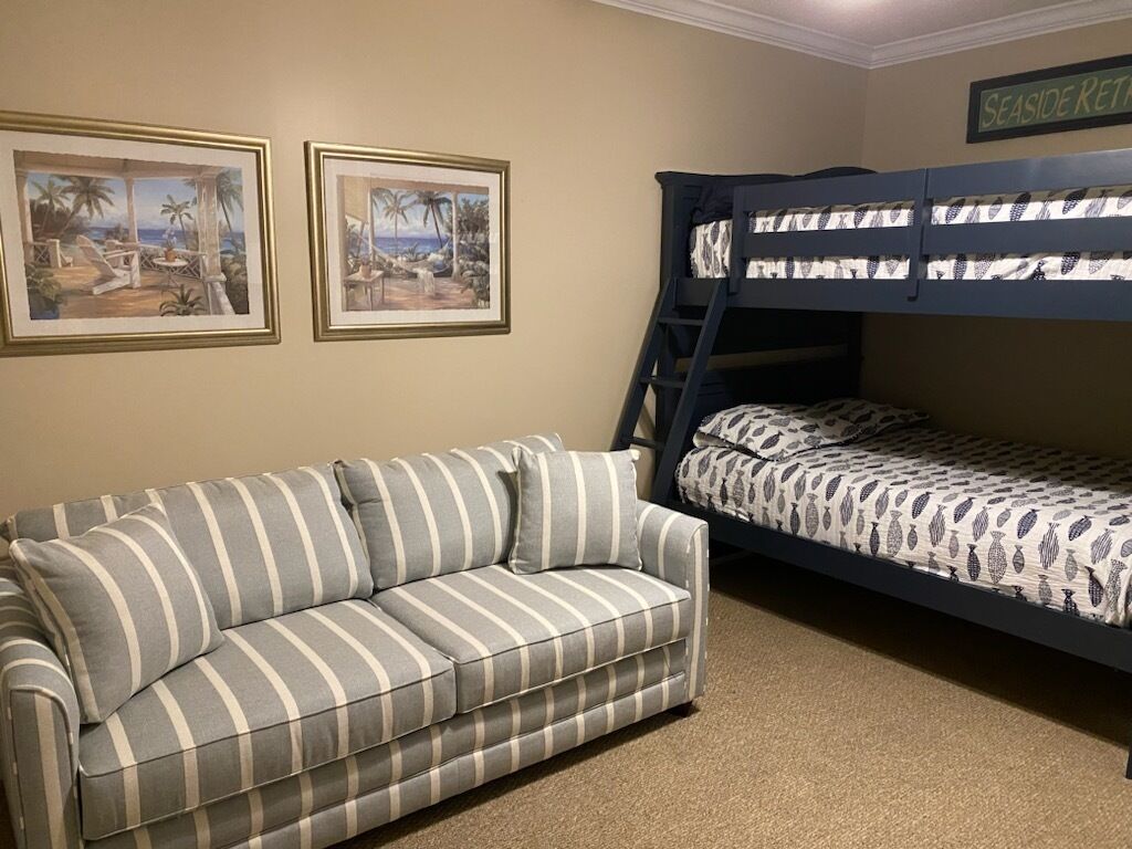 Een kamer met een stapelbed, een gestreepte bank en twee ingelijste foto’s aan de muur.