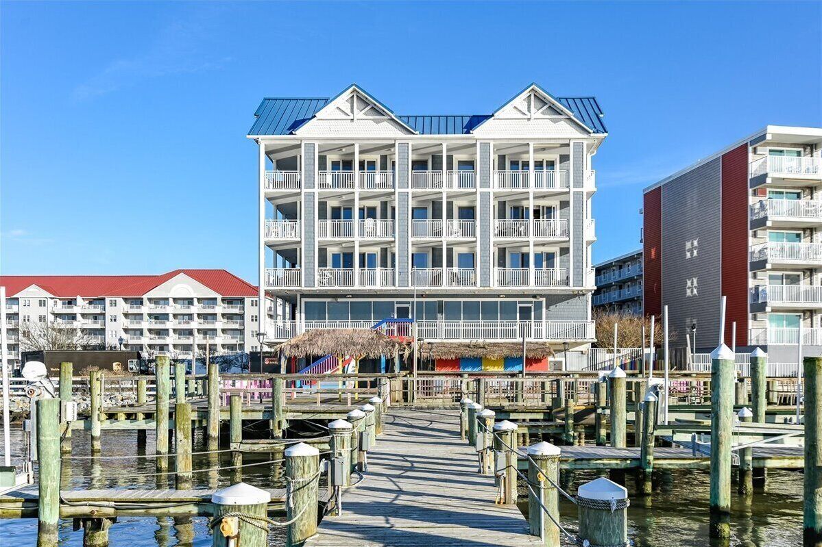 A waterfront hotel with multiple balconies, a thatched-roof structure, and a dock area.