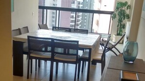 Un espace repas moderne doté d’une grande fenêtre, d’une table à manger, de chaises et d’un appareil de climatisation.