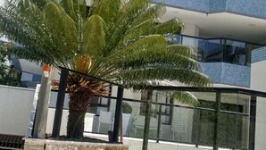 Un bâtiment moderne avec une façade en verre et un palmier au premier plan.