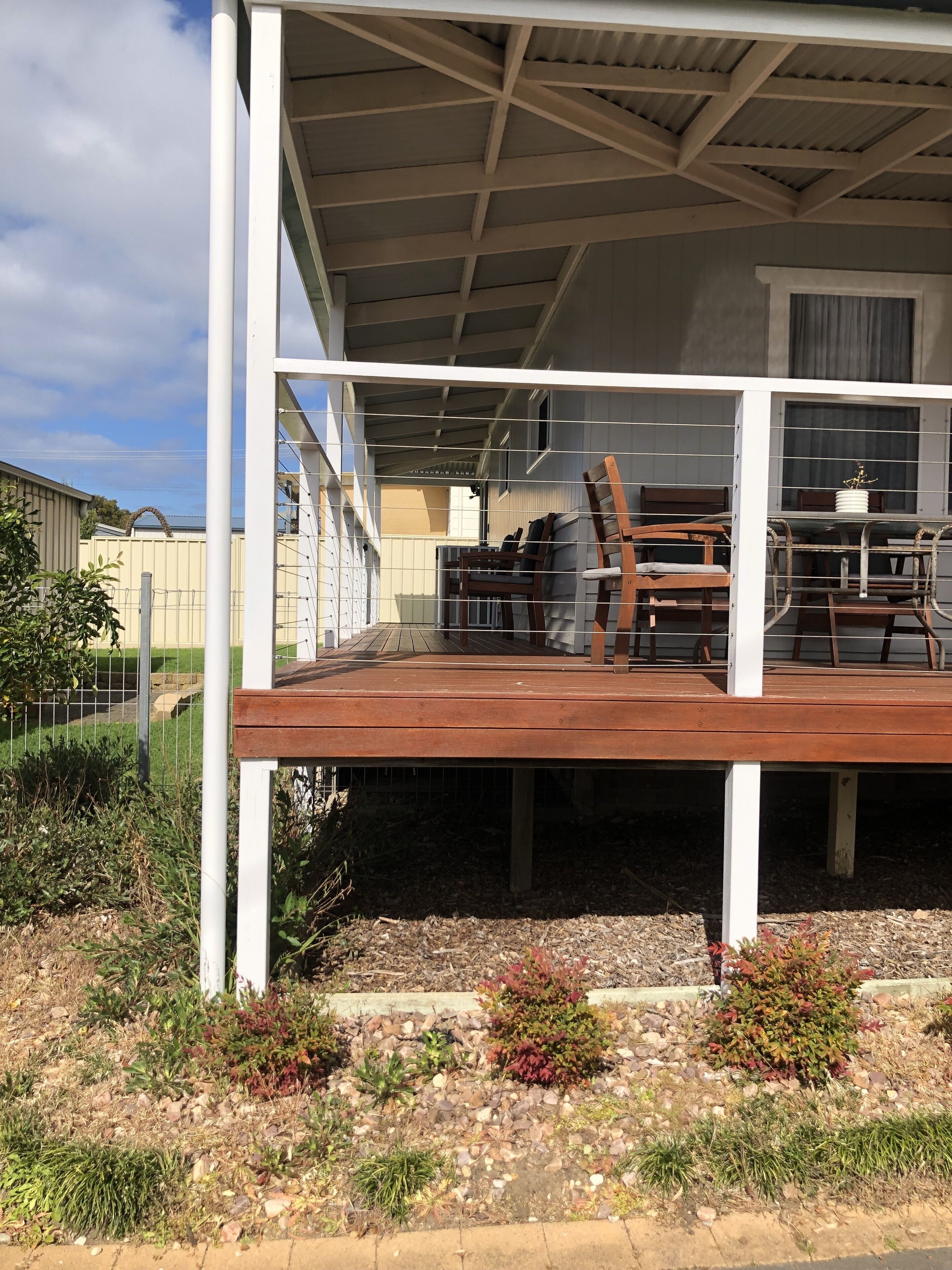 Un espace extérieur abrité, doté d’une terrasse en bois, de sièges et offrant une vue sur un immeuble d’habitation.