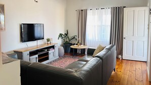A modern living room with a flat-screen TV, a sofa, a coffee table, and a ceiling fan.