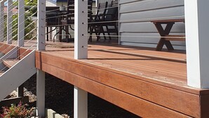 A covered outdoor area with a wooden deck, white railings, and a window with the number 2.