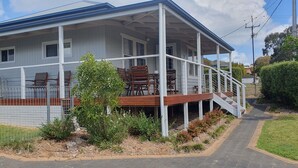 A two-story house with a covered porch, outdoor seating, and a fenced garden area.
