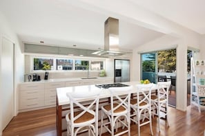 Une cuisine moderne dotée d’un îlot central, de meubles blancs et d’une hotte de cuisinière en acier inoxydable.