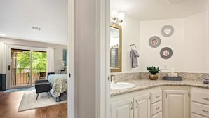 A modern bathroom with a granite countertop, a large mirror, and decorative wall plates. - Peaceful Sports Village Condo | King Bed, Balcony & Pools (St. George)