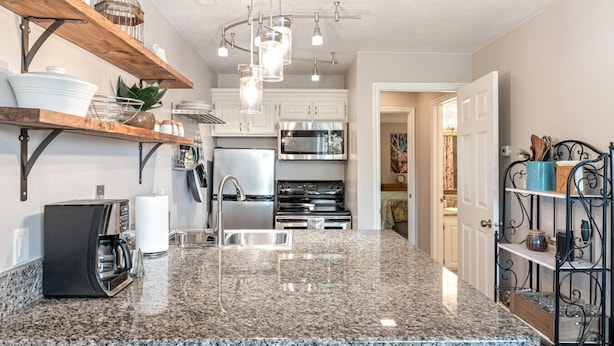 A kitchen with granite countertops, stainless steel appliances, and a hanging light fixture. - Peaceful Sports Village Condo | King Bed, Balcony & Pools (St. George)