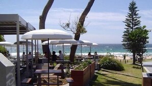 Ein Außenbereich mit Sonnenschirmen, Tischen und Stühlen mit Blick auf den Strand.