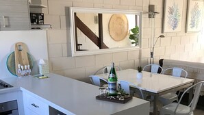 Eine moderne Küche mit weißen Schränken, einer zentralen Kochinsel und einem Essbereich mit Tisch und Stühlen.