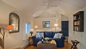 A cozy living room with a blue sofa, a wooden coffee table, and a ceiling fan.