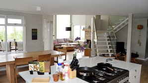 A modern kitchen with a stove, dining table, and chairs. There is a staircase leading to another level.