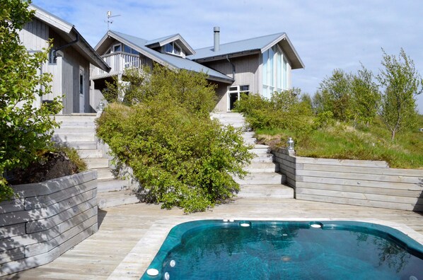 Une maison moderne dotée d’une piscine, d’une terrasse en bois et d’un escalier menant à l’entrée.