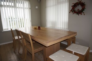Une table de salle à manger en bois, avec quatre chaises et deux bancs rembourrés.