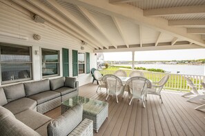 A covered porch with a sofa, chairs, and a glass-top table.
