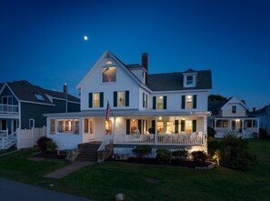 A two-story house with a porch and a flag.