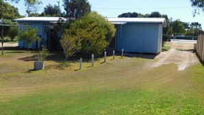 A small, single-story building with a flat roof, surrounded by a fenced area with sparse grass and a few trees.