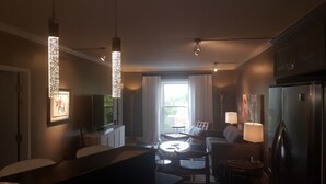 Une cuisine moderne avec un coin repas, dotée de luminaires suspendus, d’un réfrigérateur et offrant une vue sur l’extérieur.