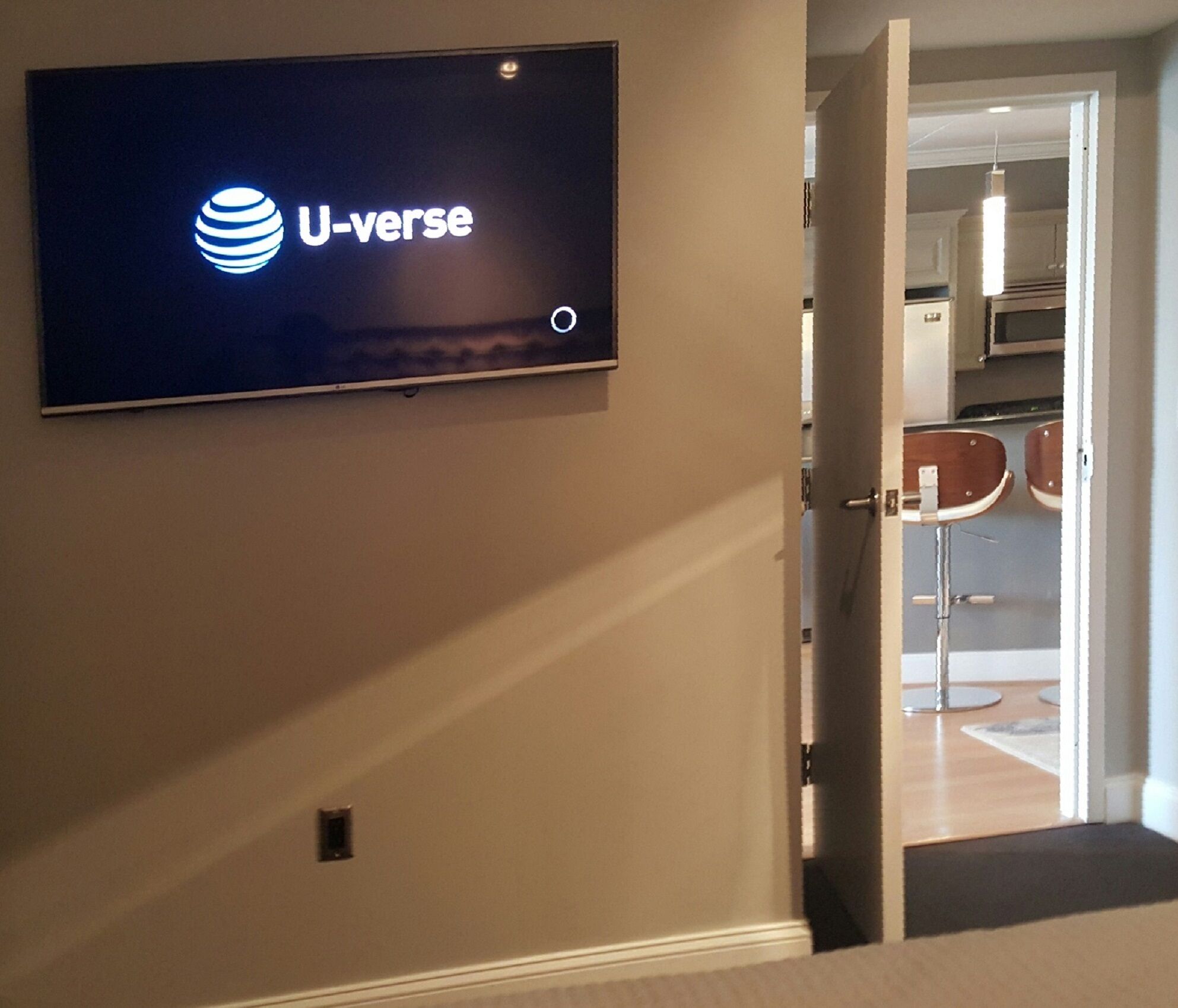 Un téléviseur à écran plat fixé au mur, sur lequel est affiché le logo U-verse.