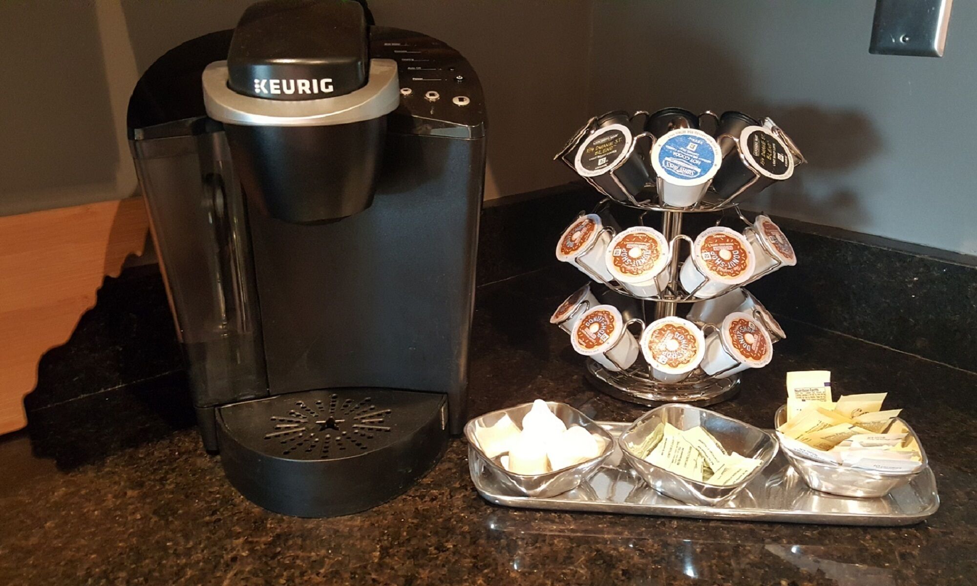 A Keurig coffee machine and a tray with disposable coffee pods and sugar packets.