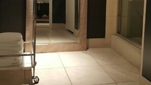 Une salle de bain avec un grand miroir, un porte-serviettes et un espace douche.