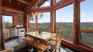 L’intérieur d’un chalet rustique, avec une table à manger en bois, des bancs et un coin cuisine.