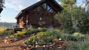 Une cabane en rondins dotée d’une grande fenêtre et d’une terrasse.
