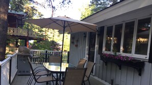 An outdoor patio with a glass table, chairs, and a large umbrella. - Location! Walk to Cranmore and Town! (Conway)