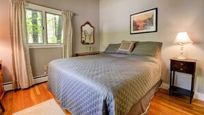 A bedroom with a large bed, a bedside table with a lamp, a window with curtains, and a framed picture on the wall. - Location! Walk to Cranmore and Town! (Conway)