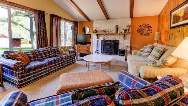 A cozy living room with a fireplace, plaid sofas, and a television. - Location! Walk to Cranmore and Town! (Conway)