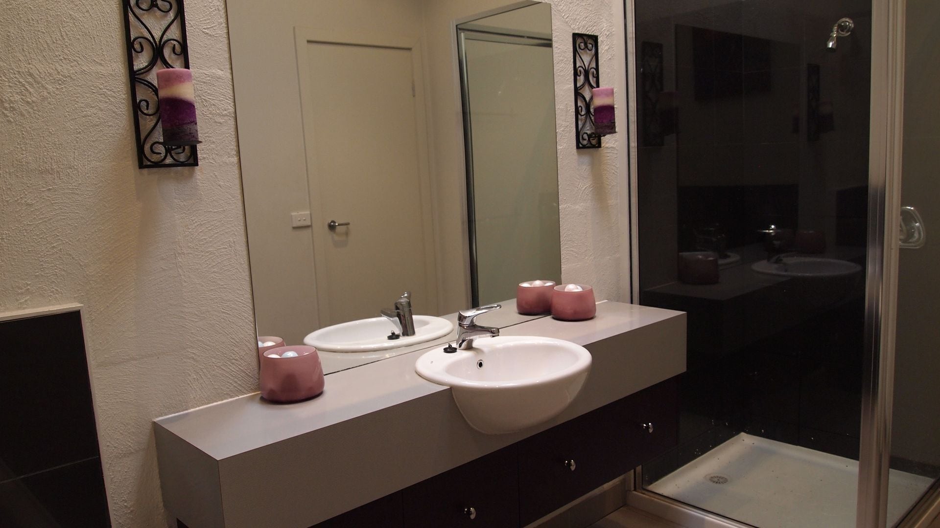 Een badkamer met twee wasbakken, een spiegel en een douche.