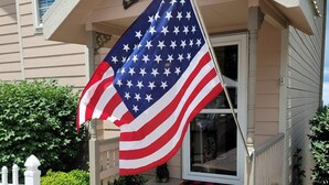 Ein Haus mit Veranda, einem Willkommensschild und einer US-amerikanischen Flagge.