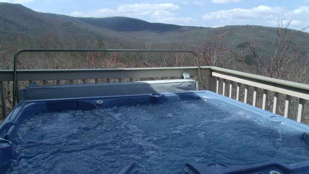 Ein Whirlpool mit Bedienfeld, umgeben von einem Metallgeländer, mit Blick auf eine gebirgige Landschaft.