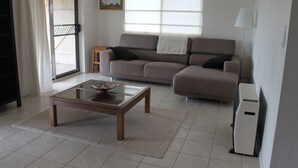 A living room with a sofa, a glass coffee table, a lamp, and a computer. - The Winerack- spectacular views (Mudgee)