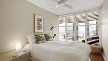A bedroom with a bed, bedside table, lamp, and a view through the window.