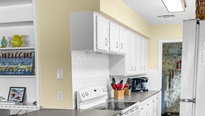 A modern kitchen with white cabinetry, a central island, and a wooden floor. - Waterfront, gorgeous sunsets, sandy beach, dogs allowed. (Kingsland)