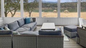 A covered outdoor seating area with wicker furniture and a view of a lake. - Waterfront, gorgeous sunsets, sandy beach, dogs allowed. (Kingsland)