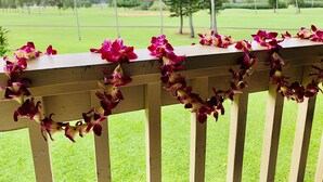 Een houten leuning met roze en witte bloemen.