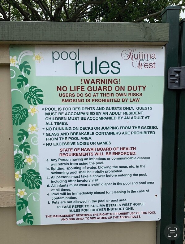 Un panneau indiquant les règles à respecter au bord de la piscine de Kuilima Estates West, notamment l’absence de sauveteur, l’interdiction de courir ou de sauter depuis le kiosque, ainsi que l’interdiction des récipients en verre et des nuisances sonores excessives.