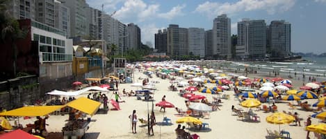 A beach with numerous umbrellas and people.