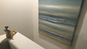 Ein Zimmer mit weißer Wand und einem Bild einer Strandansicht.