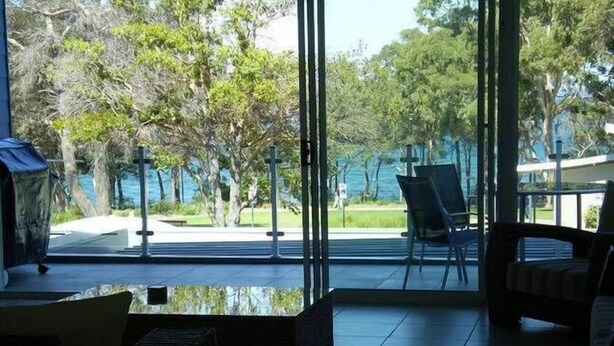Une pièce moderne avec une grande fenêtre en verre, un canapé, un fauteuil et une petite table.