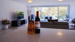 Un salon moderne avec une table blanche, une bouteille de vin et une boîte à vin.