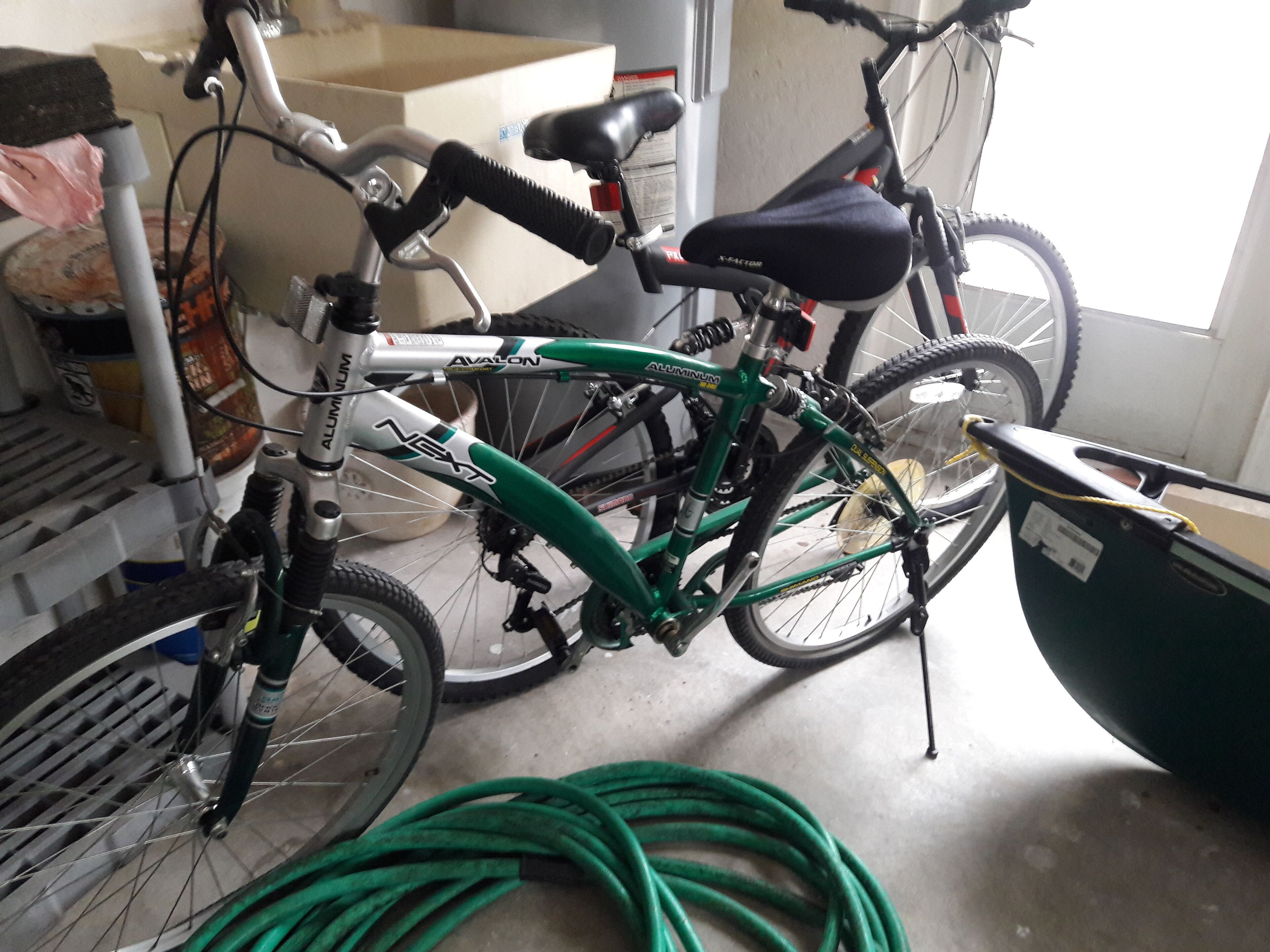 Ein Fahrrad mit grünem Rahmen und schwarzem Sattel, an einer Wand in einem Raum mit Betonboden angelehnt.