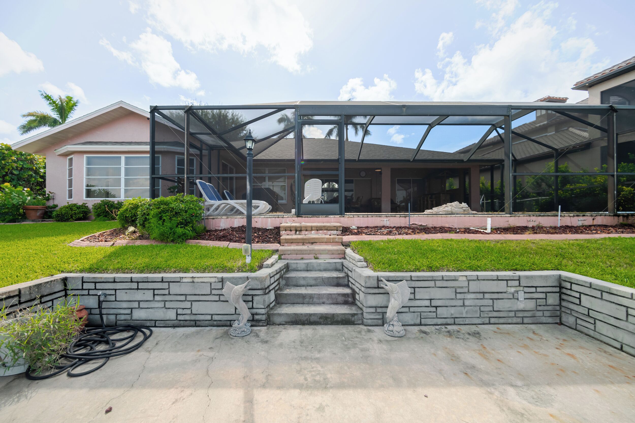 A house with a covered patio, a stone staircase, and a lawn.