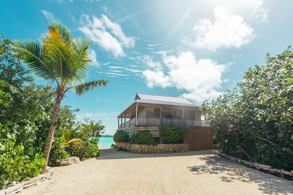 A beach house with a balcony, surrounded by tropical vegetation and a clear view of the ocean. - Tree House Atmosphere on Chalk Sound National Park (Providenciales)