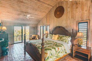 A wooden-paneled bedroom with a large bed, a ceiling fan, and a view through the open door. - Tree House Atmosphere on Chalk Sound National Park (Providenciales)