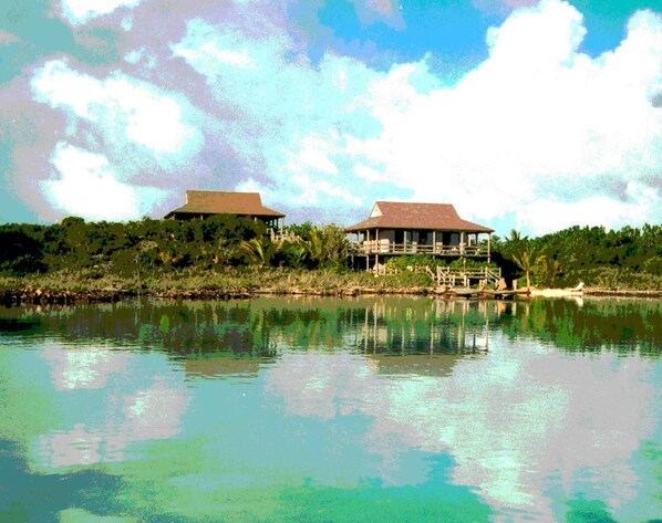 A lakeside property with two main buildings, one with a balcony and the other with a covered patio. - Tree House Atmosphere on Chalk Sound National Park (Providenciales)